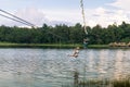 Young woman crossing a lake in zip line in Chiang Mai