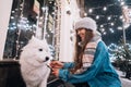 A young woman crouched beside a dog on a winter street.