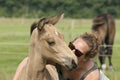 Young woman cuddling with her best friend, falcon color stallion foal, share a loving moment
