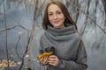 Young woman with a cup of coffee and a bouquet of autumn leaves in the forest near a pond in a fine rain Royalty Free Stock Photo