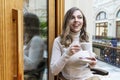 Young woman with a cup of coffee in a cafe laughs. Beautiful blonde in a beige sweater. Business meeting and breakfast Royalty Free Stock Photo