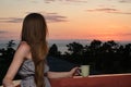 Young woman with a cup in her hand looking at sea and sunset. Side view