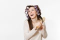 Young woman with curlers using combing with comb her hair isolated on white background. Crazy makeup with set facial Royalty Free Stock Photo