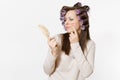 Young woman with curlers using combing with comb her hair isolated on white background. Crazy makeup with set facial Royalty Free Stock Photo