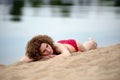 Young woman with curling hair lies on a beach