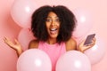 A young woman with curly Afro hair is very happy about the received message on her smartphone, she screams with joy Royalty Free Stock Photo