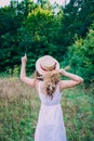 Young woman with curly hair in a hat. Slender girl in a hat with her back turned. Photo of a girl from the back