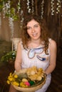 Young woman with curly hair holding basket with ducklings, painted Easter eggs, dandelions Royalty Free Stock Photo