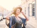 Young woman with curly hair walking on city street at sunset wearing hat and coat, enjoying happy moment on european street Royalty Free Stock Photo