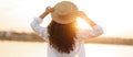Young woman with curly hair wearing a hat in sunset light looking far away on the sea. Photo from behind. Royalty Free Stock Photo