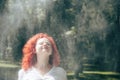 Young woman with curly, red hair framed her face under refreshing drops of water Royalty Free Stock Photo