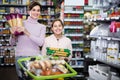 Young woman customer with girl looking for pasta in supermarket Royalty Free Stock Photo