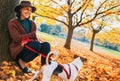 Young woman with cute dog sitting under tree in autumn park Royalty Free Stock Photo