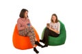 Young woman and cute girl sitting on beanbag chairs and drinking