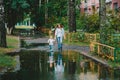 Young woman and little boy walking on a city street in a summer park after rain Royalty Free Stock Photo