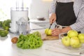 Young woman cutting fresh apple for juice at table in kitchen, closeup Royalty Free Stock Photo