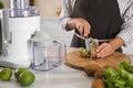 Young woman cutting fresh kiwi for juice at table in kitchen, closeup Royalty Free Stock Photo