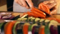 Young woman cutting juicy red tomato. Cooking homemade ratatouille