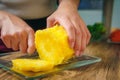 Young Woman cutting a pineapple on a wooden table in the kitchen Royalty Free Stock Photo