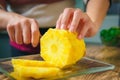 Young Woman cutting a pineapple on a wooden table in the kitchen Royalty Free Stock Photo