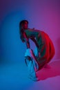 Young woman dancer in stylish youth clothes in gym shoes dancing and posing in a room with bright neon blue-pink color.Attractive Royalty Free Stock Photo