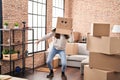 Young woman dancing with funny cardboard box on head at new home