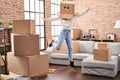 Young woman dancing with funny cardboard box on head at new home