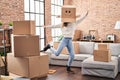 Young woman dancing with funny cardboard box on head at new home