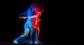 Young woman dancing hip-hop in sportive style clothes isolated on dark background at dance hall in mixed neon light Royalty Free Stock Photo