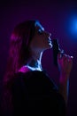 A young woman in the dark in a club holds a gun. Party girl in blue and pink light Royalty Free Stock Photo