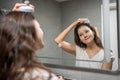 Young woman with dark curly hair doing self hair scalp massage with scalp massager or hair brush for hair growth Royalty Free Stock Photo