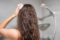 Young woman with dark curly hair doing self hair scalp massage with scalp massager or hair brush for hair growth Royalty Free Stock Photo