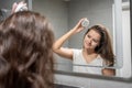 Young woman with dark hair doing self hair scalp massage with scalp massager or hair brush for hair growth stimulating Royalty Free Stock Photo