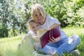 Young woman with a daughter are reading a book in a park on a sunny summer day. Love and tenderness Royalty Free Stock Photo