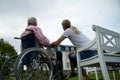 Young woman daughter with senior father in wheelchair at nursing retirement home