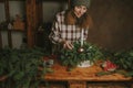 Young woman decorating Christmas flower arrangement. Royalty Free Stock Photo