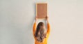 Young woman decorating interior, hanging blank a photo frame mockup on white wall in a new house Royalty Free Stock Photo