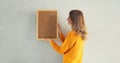 Young woman decorating interior, hanging blank a photo frame mockup on white wall in a new house Royalty Free Stock Photo