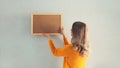 Young woman decorating interior, hanging blank a photo frame mockup on white wall in a new house Royalty Free Stock Photo