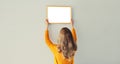 Young woman decorating interior, hanging blank white photo frame mockup on white wall in new home Royalty Free Stock Photo