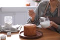 Young woman decorating traditional Easter cake with glaze in kitchen, closeup. Space for text Royalty Free Stock Photo