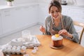 Young woman decorating traditional Easter cake in kitchen. Space for text Royalty Free Stock Photo