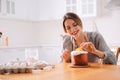 Young woman decorating traditional Easter cake in kitchen. Space for text Royalty Free Stock Photo