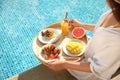 Young woman with delicious breakfast on tray near swimming pool, closeup Royalty Free Stock Photo