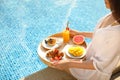 Young woman with delicious breakfast on tray near swimming pool, closeup Royalty Free Stock Photo