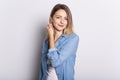 Young Woman in Denim Shirt and Jeans, Leaning Against Gray Wall Background Royalty Free Stock Photo