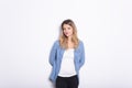 Young Woman in Denim Shirt and Jeans, Leaning Against Gray Wall Background Royalty Free Stock Photo