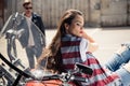 Young woman in denim vest sitting on motorcycle and stylish man in sunglasses standing behind Royalty Free Stock Photo