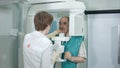 Young woman dentist peparing patient for analyzes a dental panoramic x-ray film in clinic