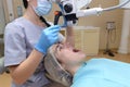 Young woman dentist treating root canals using microscope in the dental clinic. Man patient lying on dentist chair with open mouth Royalty Free Stock Photo